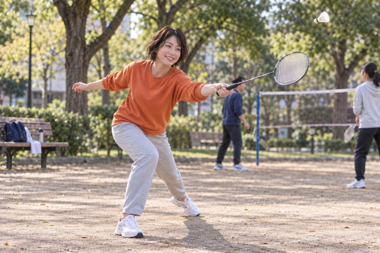 仲間と屋外でバドミントンを楽しむ女性